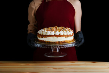 cake with walnut and cream cheese closeup. woman confectioner hold carrot layer dessert. gloved hands of a pastry chef