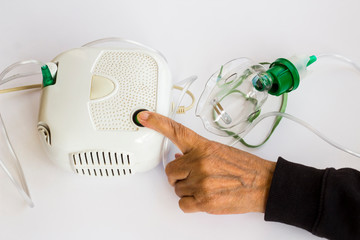 Home type mini air machine with oxygen mask on hand touches on-off button of older person. - obrazy, fototapety, plakaty