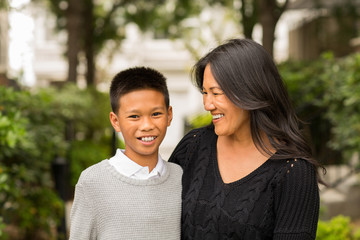 Asian mom smiling and hugging her son.