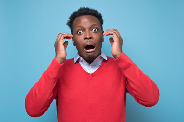 Surprised emotional young black man having stunned fascinated look, opening mouth widely shocked...