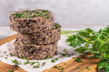 Raw veggie burger with black beans on wood countertop.