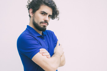 Upset offended guy with folded arms looking at camera. Handsome bearded young man in blue casual...