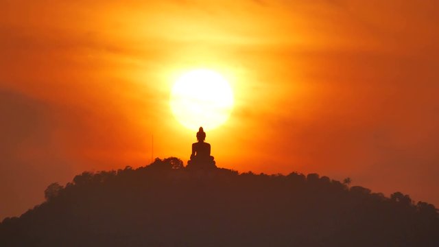 hue sunset behind Phuket buddha statue on hilltop mountain with many silhouette leaves trees, beautiful golden twilight sky background in evening time