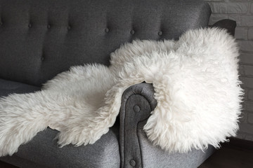 White sheep skin on a gray sofa. A cozy place to relax in the apartment