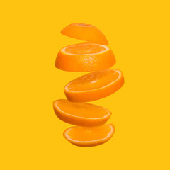 Creative concept with flying orange. Sliced orange on yellow background.