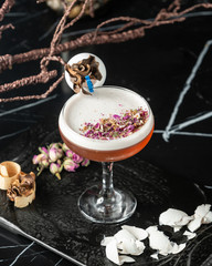 top view of foamy cocktail garnished with rose petal pieces and egg shells