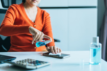 Woman spraying alcohol to mobile phone,Preventive measures against coronavirus,Covid-19