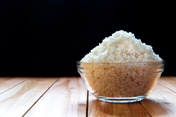 Sea salt in bowl on wooden on black background, Sea salt is salt that is produced by the evaporation of seawater. Used as a seasoning in foods, cooking, cosmetics and for preserving food..