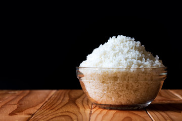 Sea salt in bowl on wooden on black background, Sea salt is salt that is produced by the evaporation of seawater. Used as a seasoning in foods, cooking, cosmetics and for preserving food..