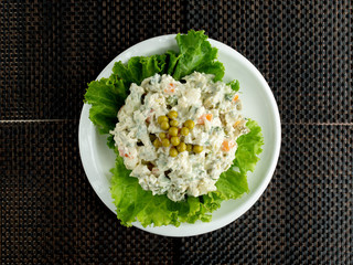 top view of olivier salad bowl garnished with lettuce