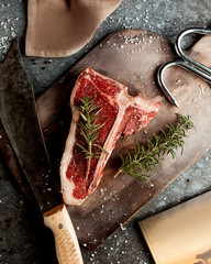 top view of raw t-bone steak garnished with rosemarine