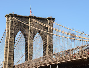 Brooklyn Bridge in New York, closeup with American flag on top.