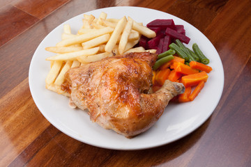 Peruvian food: pollo a la brasa or roasted chicken with french fries and cooked vegetable salad served on a white plate