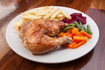 Peruvian food: pollo a la brasa or roasted chicken with french fries and cooked vegetable salad served on a white plate