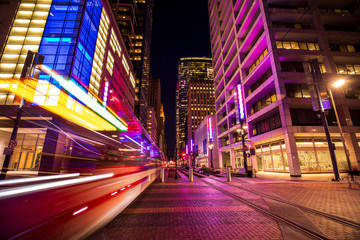 Long exposure shot of a light rail train zooming through Houston, Texas' Main Street Square.
