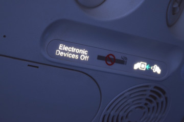Electronic sign on airplane.  Fasten your seat belt, no smoking and turn off electronic devices....