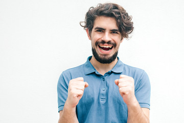 Happy overjoyed guy making winner gesture, rejoicing at good news. Handsome bearded young man in...