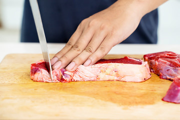 Closeup of hand chopping sirloin beef steak
