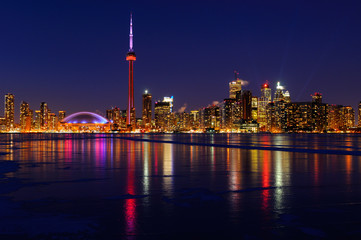 Naklejka na ściany i meble Toronto city skyline lights at night reflected on the frozen ice covered Lake Ontario