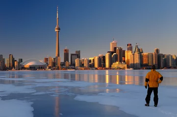 Poster Man standing on frozen Lake Ontario ice looking at Toronto city skyline at sunset © Reimar