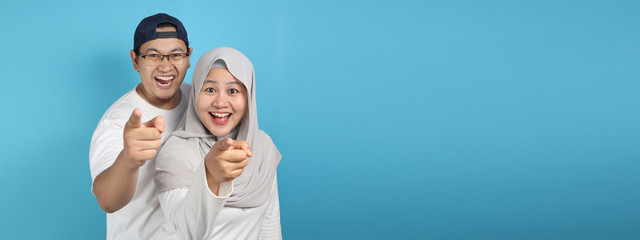 Fototapeta na wymiar Happy Asian Muslim Couple Smiling and Pointing to Camera