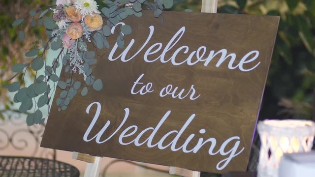 Welcom to our beginning. Maridge, frame.welcome sign on it decorated with flowers outdoor.