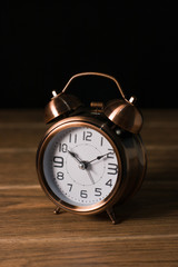 pequeño reloj despertador tipo campana de mesa y fondo oscuro