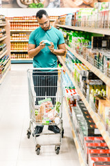 Thoughtful African American man shopping at grocery store. Serious young customer standing in aisle...