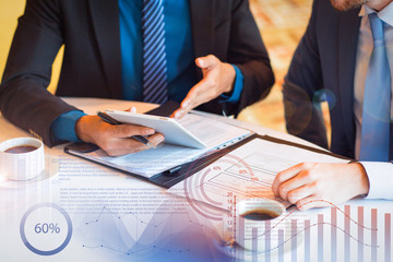 Partners discussing documents and virtual statistic graphics. Cropped view of two business men sitting at table and discussing documents and information on tablet screen