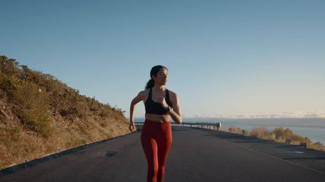 Young woman running on a mountain road. Fitness female on a morning run on a hill road.
