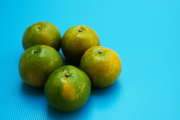 Green orange fruits on blue background