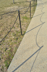Concrete walkway next to green grass with a barrier