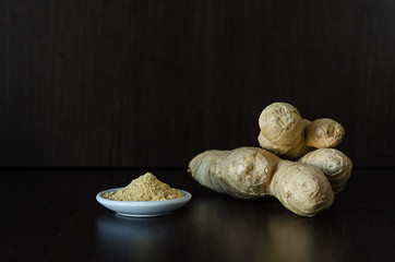 powder, ginger root on dark wooden background, copy space, soft focus