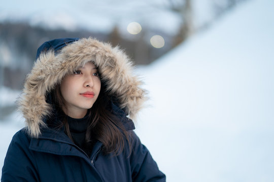Portrait of woman wearing warm coat with fur hood, having fun in winter