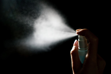 Hand using sanitizer spray, alcohol spraying disinfectant to stop spreading  coronavirus or COVID-19.