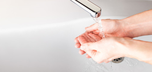  Washing hands under a stream of water  in the bathroom over the sink. Close-up of men's hands. Panoramic banner background.