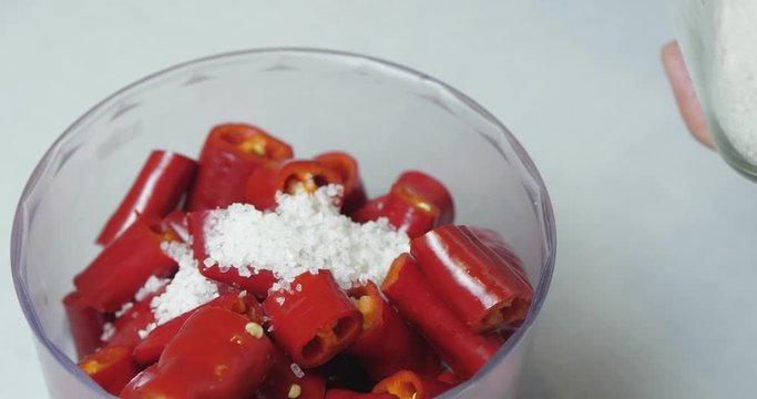 Close-up. The Cook Puts Three Tablespoons Of Coarse Sea Salt In A Blender With Chopped Hot Peppers To Grind Them For Sauce. Ingredients For Hot Chili Sauce / Cinema 4K
