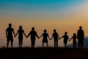 Fototapeta na wymiar The shadow of a happy family holding hands in the meadow during sunset Happy family enjoying life together outdoors Round dance celebration ceremony