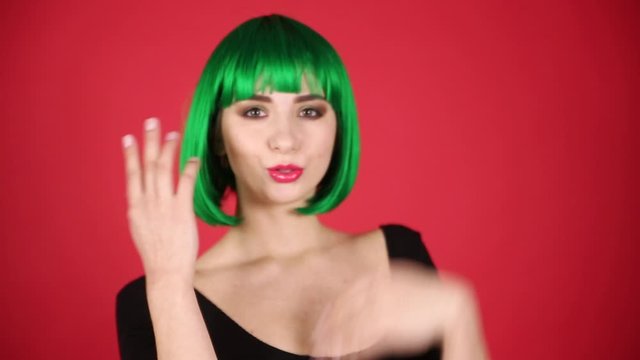 Beautiful girl in a green wig grimaces, fools around and expresses different emotions. Video