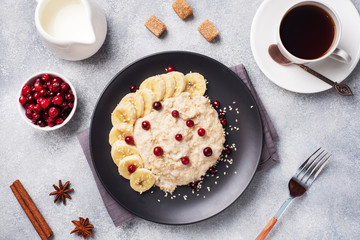 Oatmeal with milk with banana cranberries and sesame seeds. A Cup of coffee, healthy Breakfast Concept.