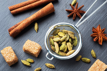 Whole grains of cardamom, a stick of cinnamon star anise and cane sugar. Close up. Ingredients for...