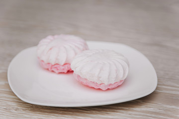 White plate with pink marshmallows on a light table. gastritis dessert