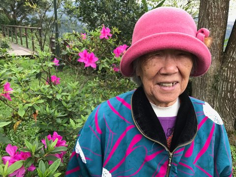 Portrait Of Smiling Senior Woman Standing Against Plants