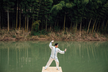 Fototapeta na wymiar Asian aged man tai chi at the lake