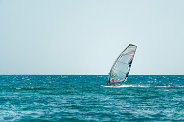 Seascape with men on surfers under sail.