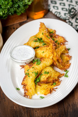 Potato pancakes served on a white plate with sour cream