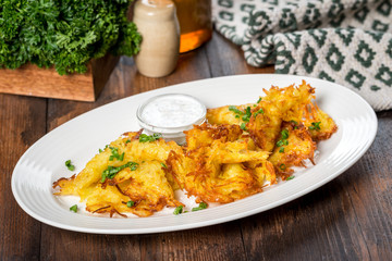 Potato pancakes served on a white plate with sour cream