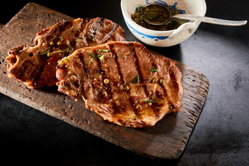 Grilled steaks on timber board with side sauce