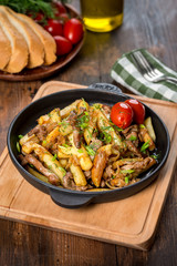 Fried potatoes with beef in a pan with dill and pickles