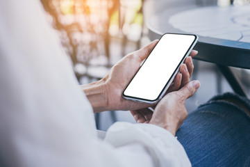 cell phone Mockup image blank white screen.woman hand holding texting using mobile on desk at coffee shop.background empty space for advertise text.people contact marketing business,technology